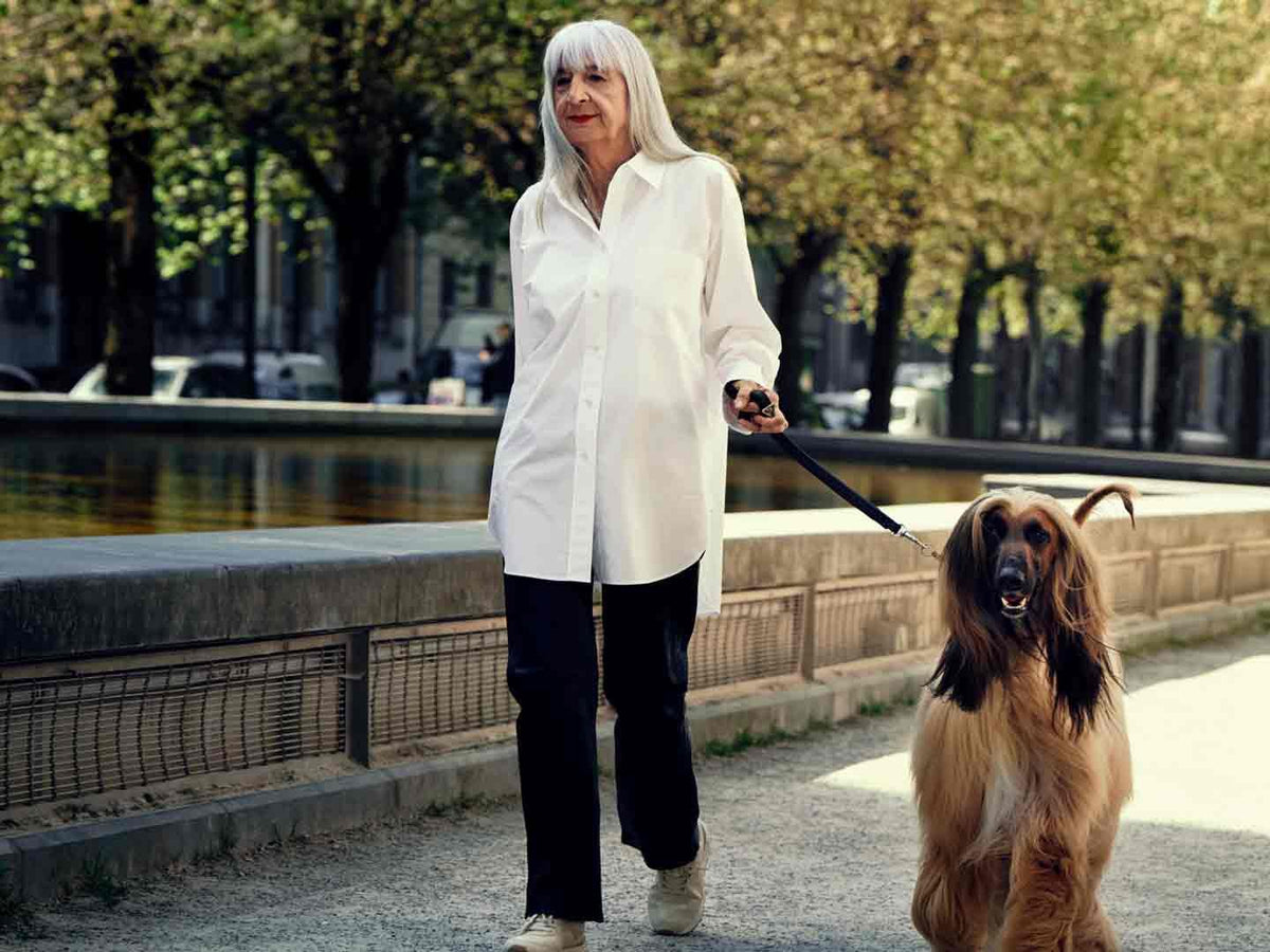 Kvinde i hvid skjorte går tur med sin hund langs en kanal