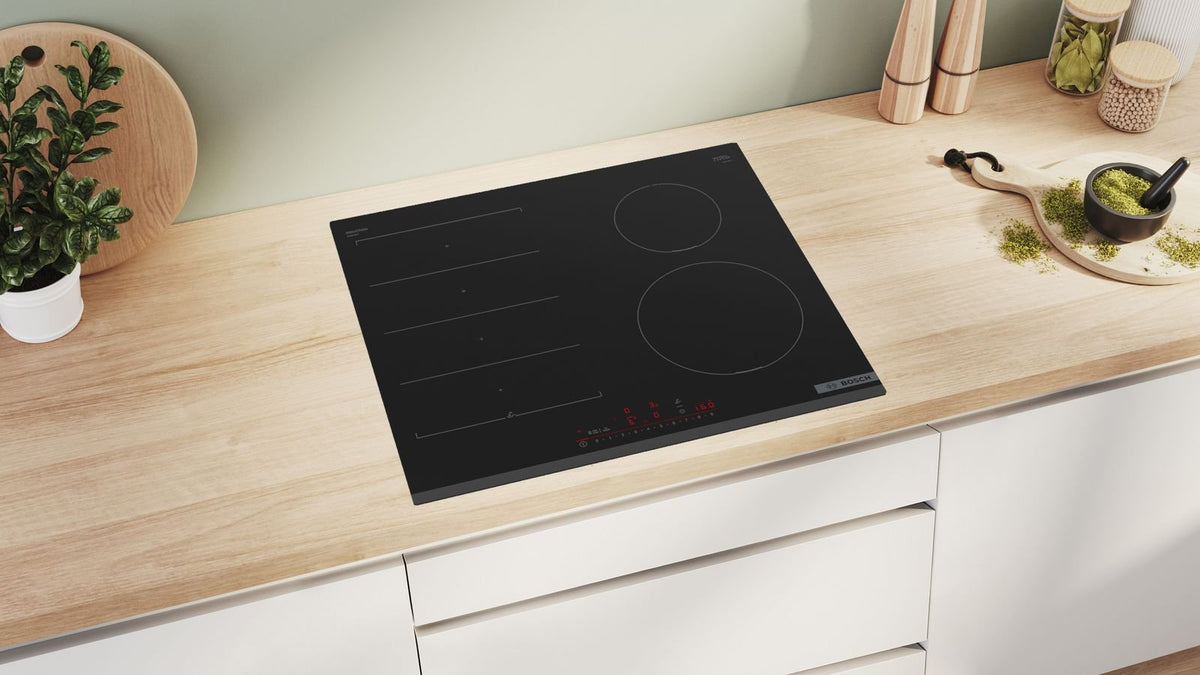 Sort Bosch induktionskogeplade med fleksible zoner i en lys bordplade af træ