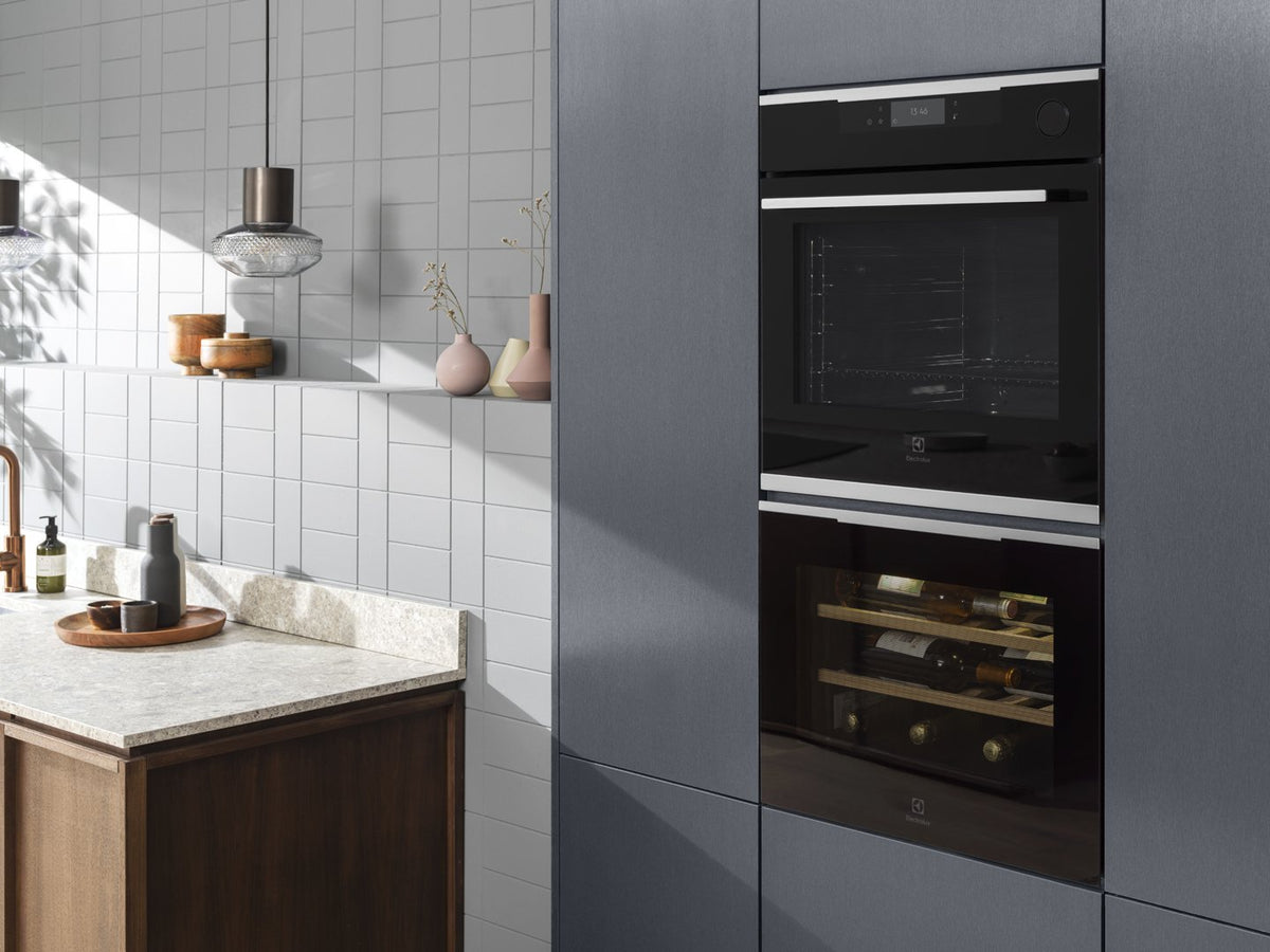Indbyggede Electrolux ovne i et lyst køkken med grå skabe