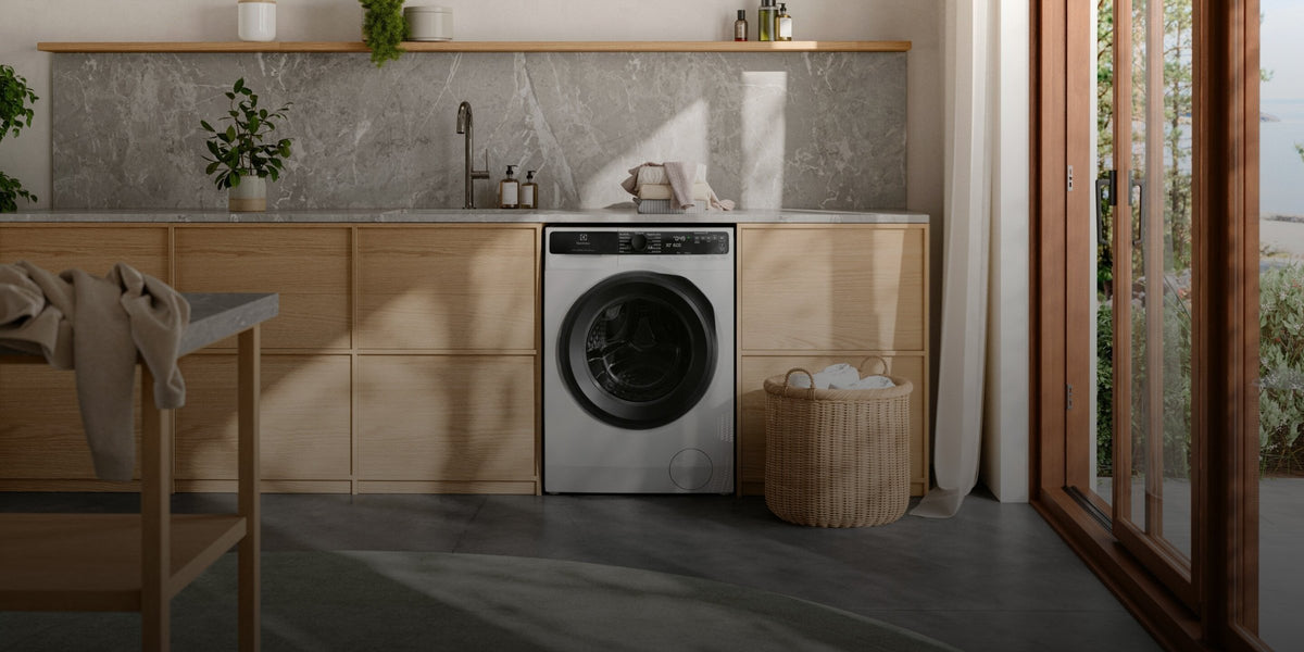 Electrolux vaskemaskine under en træbordplade i et lyst bryggers