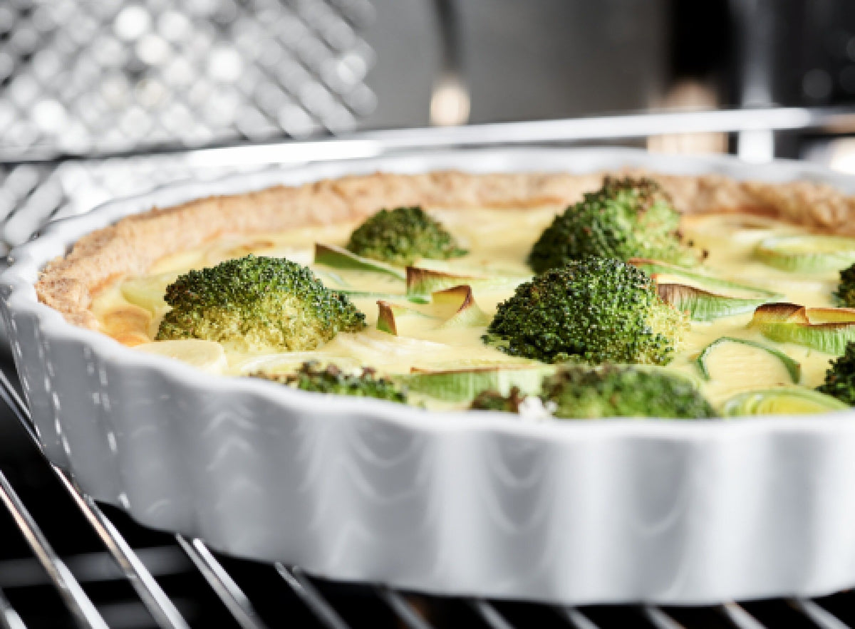 Quiche med broccoli på en rist i en belyst Gram indbygningsovn