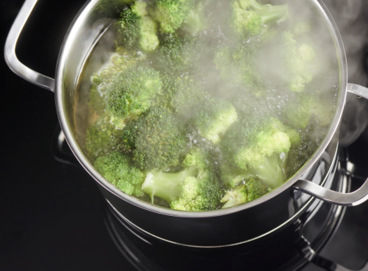 Broccoli koger i en gryde på et Gram komfur med opkogningsautomatik