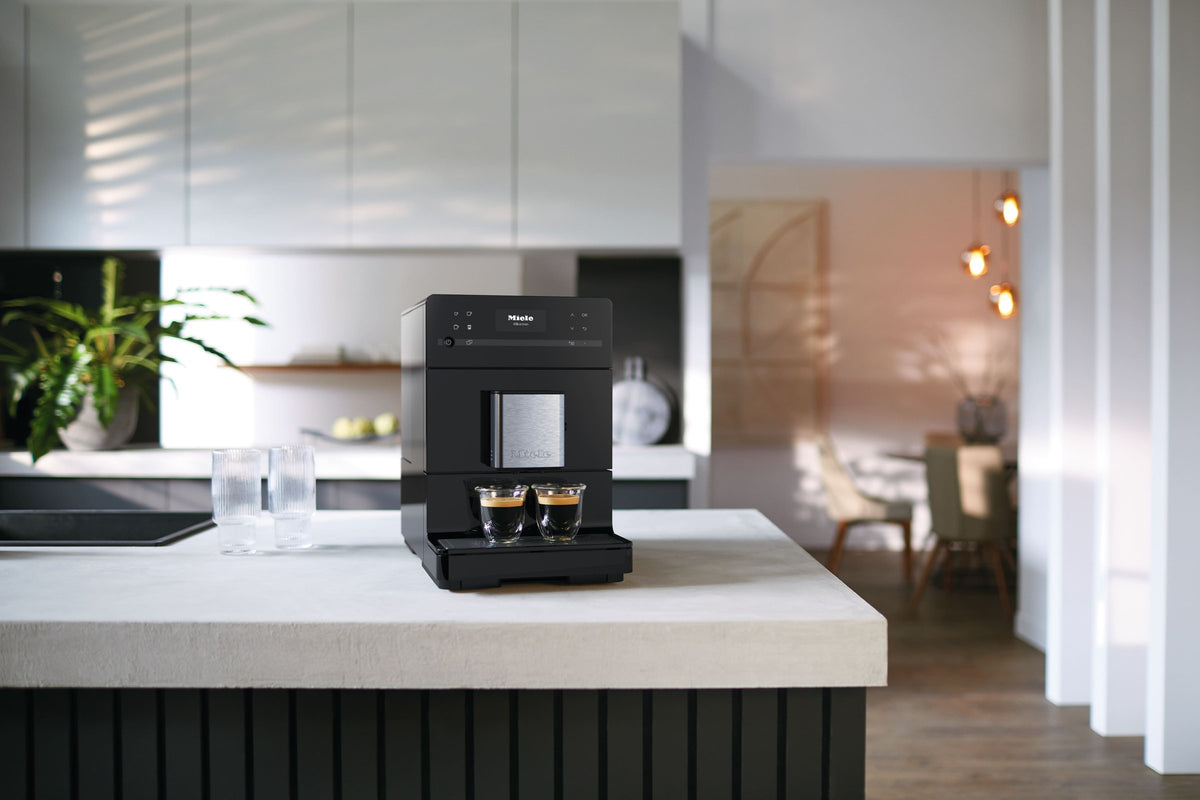 Sort Miele CM5 espressomaskine med to kopper espresso på en køkkenø