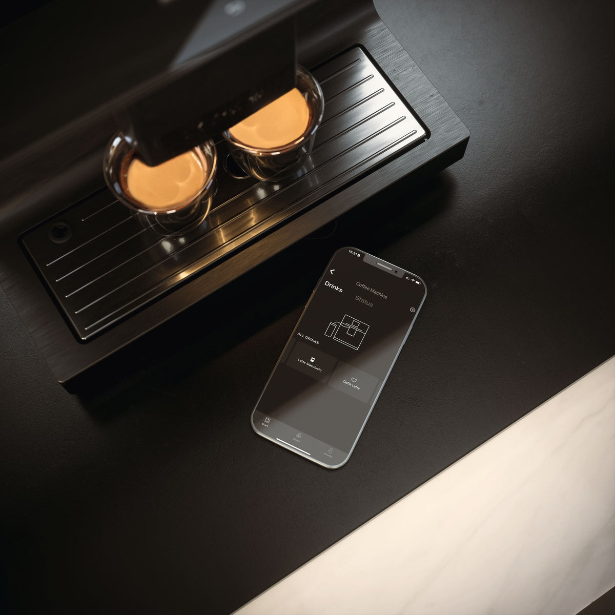 To kopper espresso under en Miele espressomaskine ved siden af en telefon med Miele-appen
