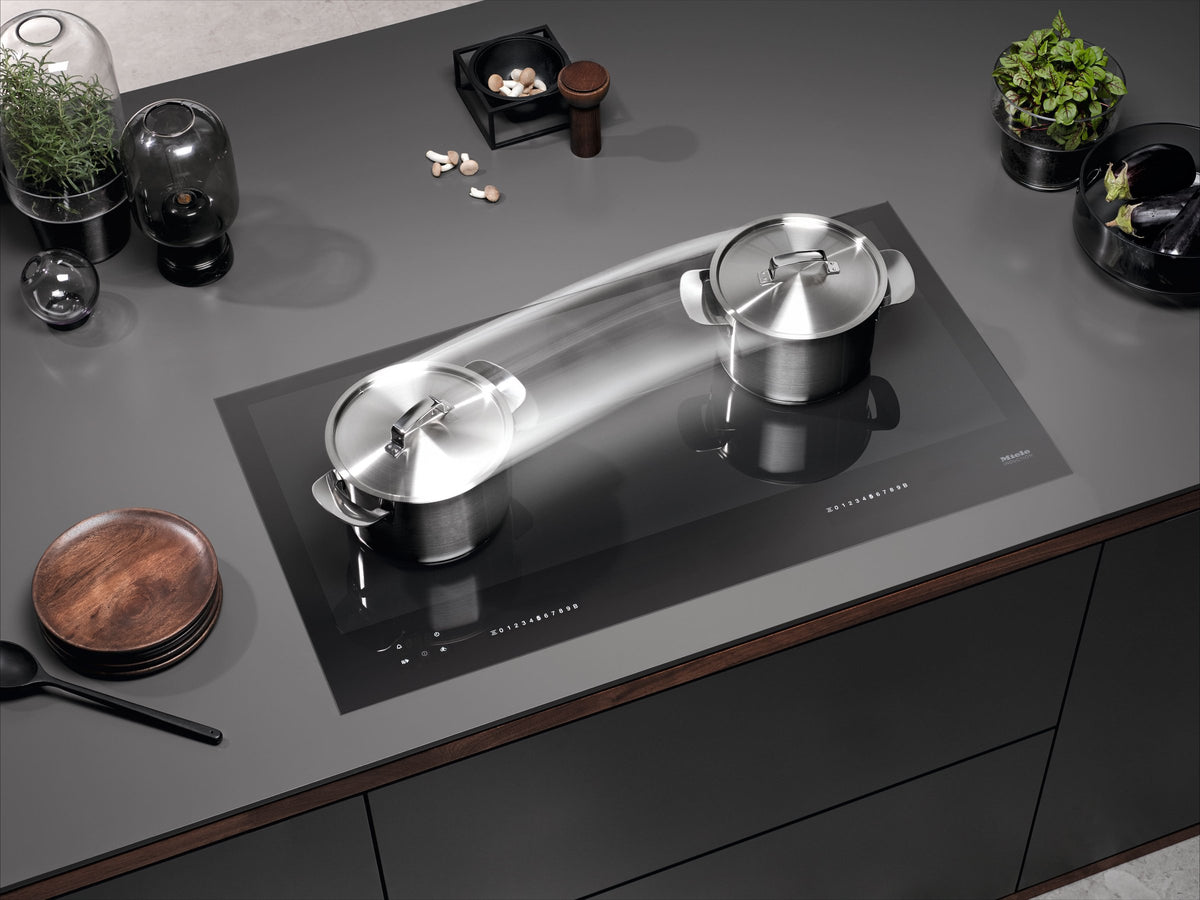 Miele induktionskogeplade med gryder og pande indbygget i en mørk bordplade