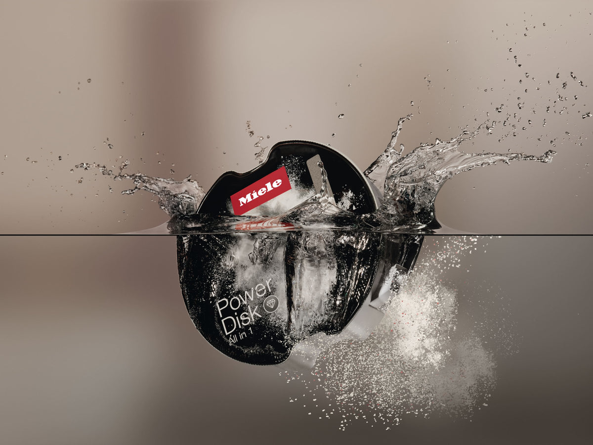 Miele PowerDisk med opvaskemiddel falder ned i vand og laver et plask