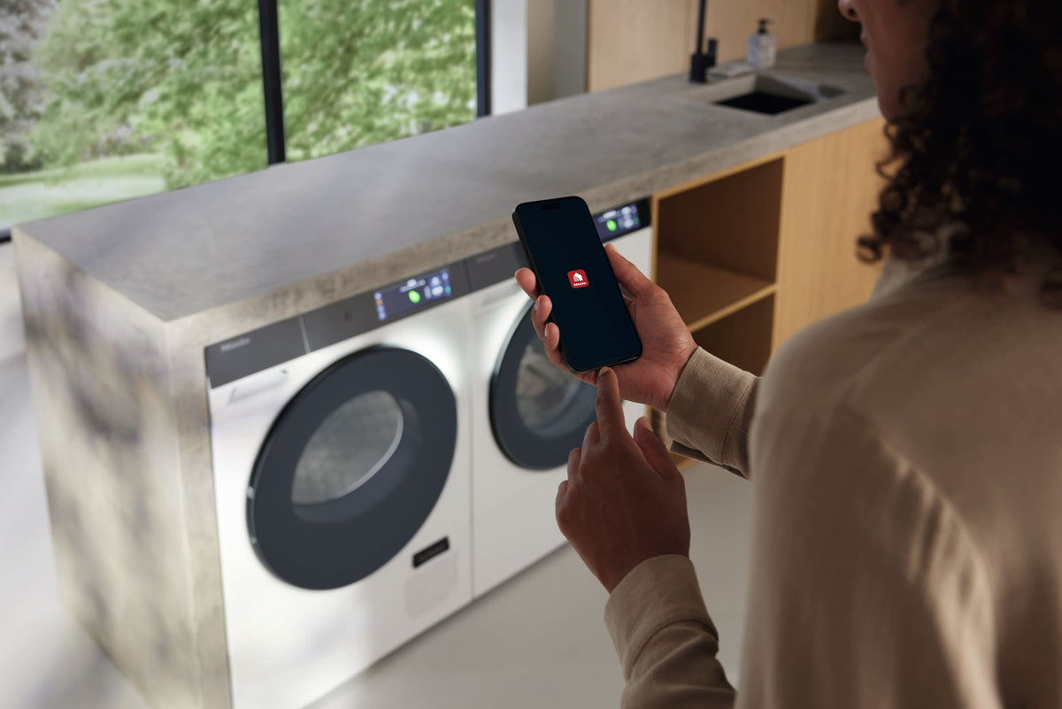Person starter en Miele vaskemaskine fra Miele-appen på mobilen