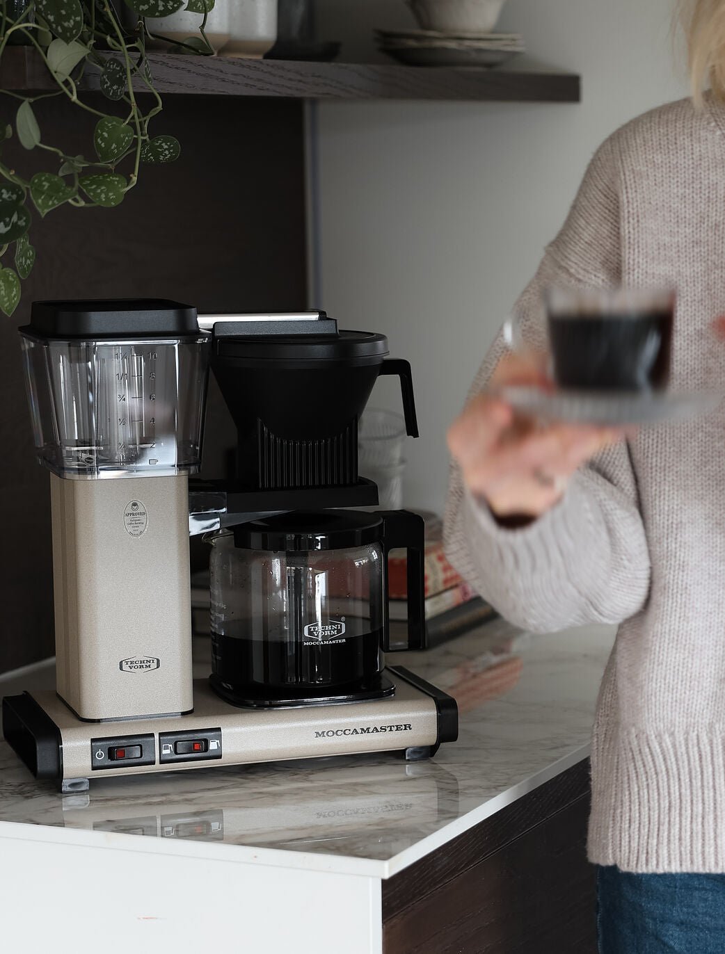 Person der hælder kaffe op fra en Moccamaster Optio kaffemaskine