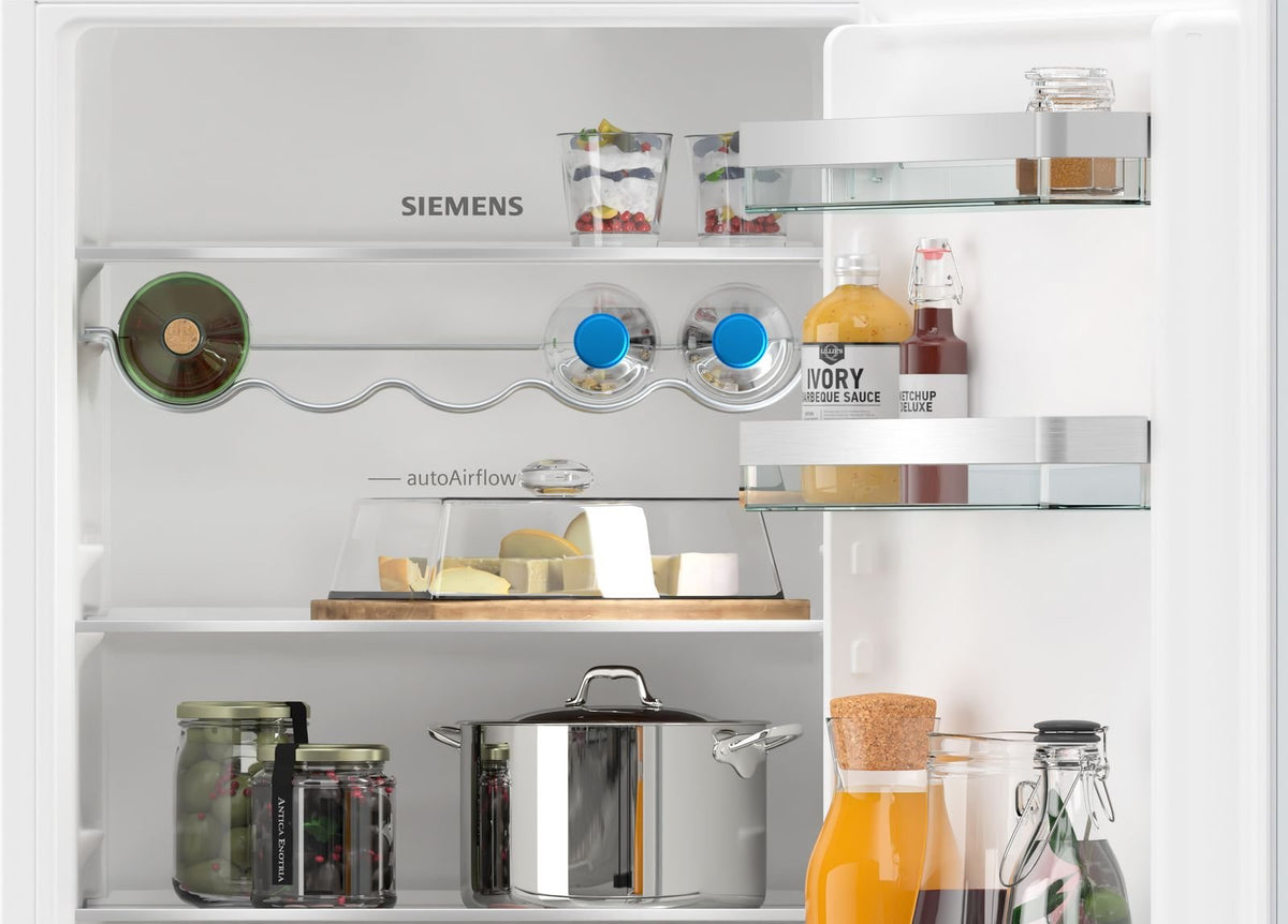 Åbent integreret Siemens køle-/fryseskab med hylder, flasker og en gryde