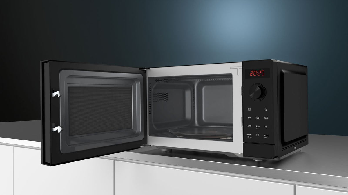 Fritstående sort Siemens mikroovn med åben låge på en hvid bordplade