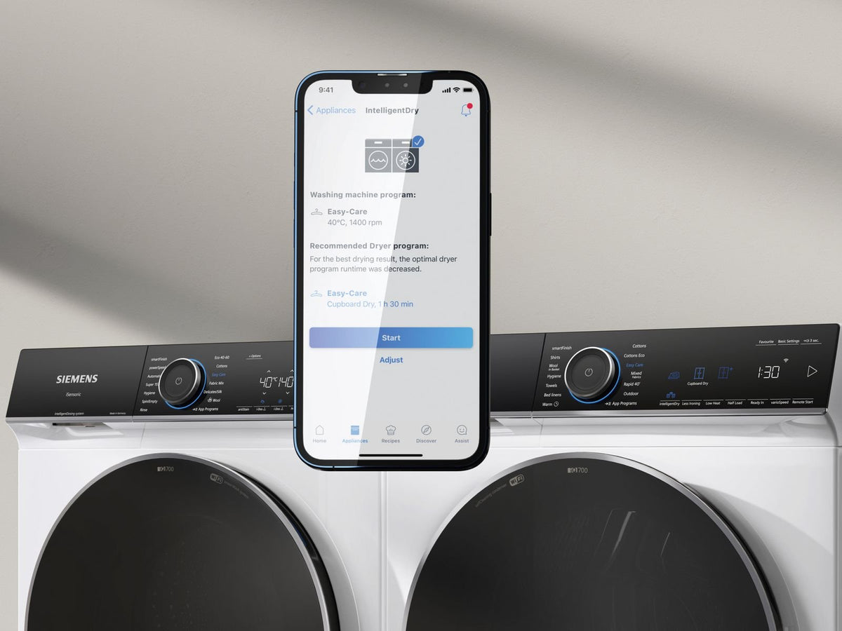 Mobil med Home Connect-appen foran en Siemens vaskemaskine og tørretumbler