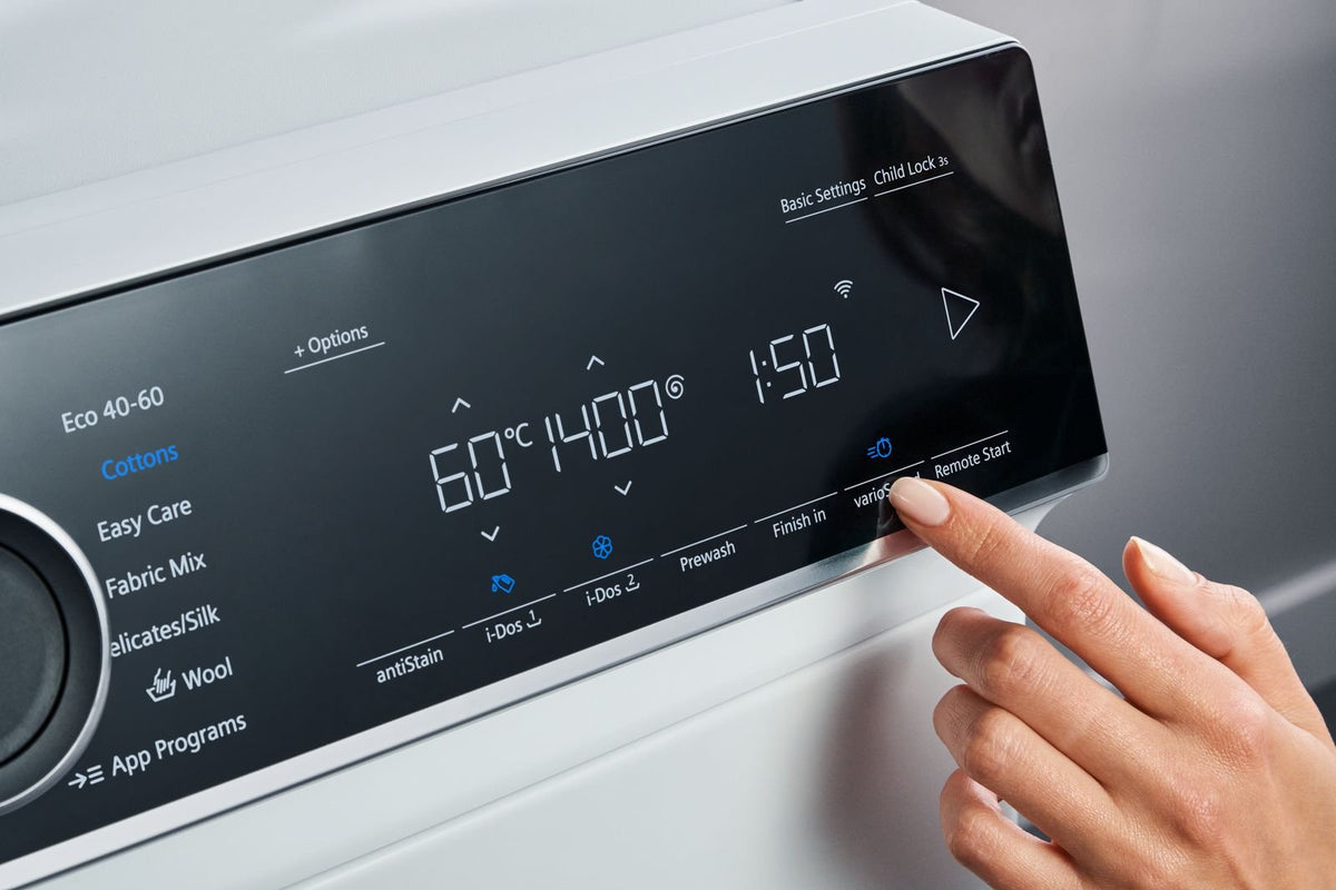 Finger betjener touch-displayet på en Siemens vaskemaskine