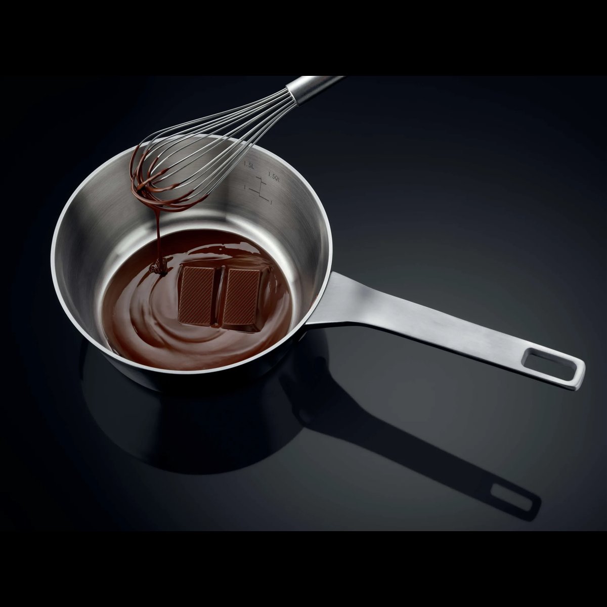 Kasserolle med smeltende chokolade og piskeris på en sort induktionskogeplade
